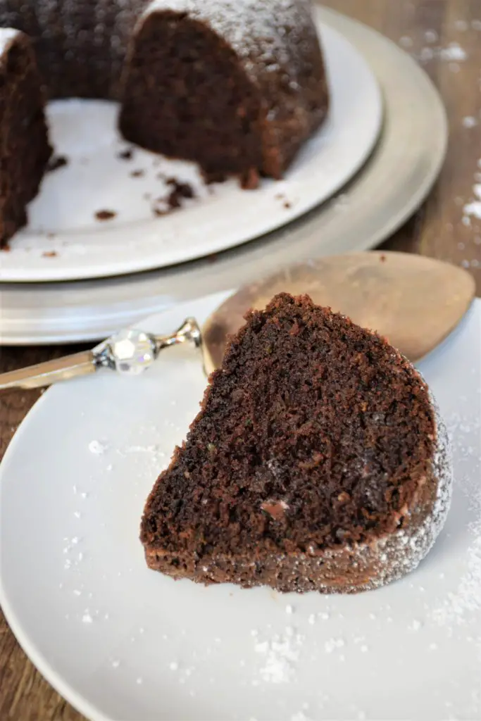 Slice of chocolate zucchini bundt cake in front of whole cake.