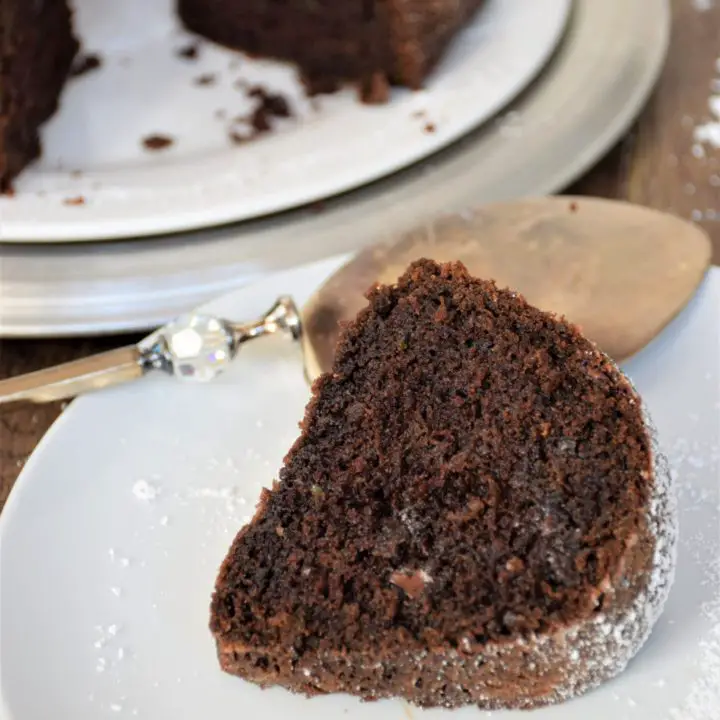 Slice of chocolate zucchini bundt cake in front of whole cake.