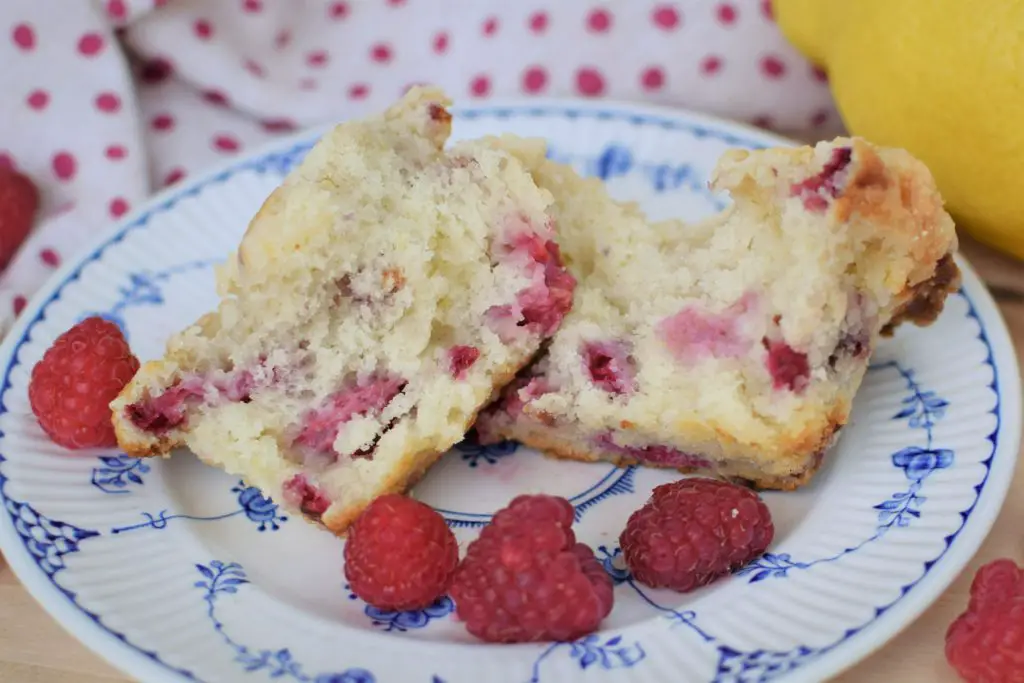 Raspberry muffin split open to show raspberries inside sitting on a plate - this bread will rise