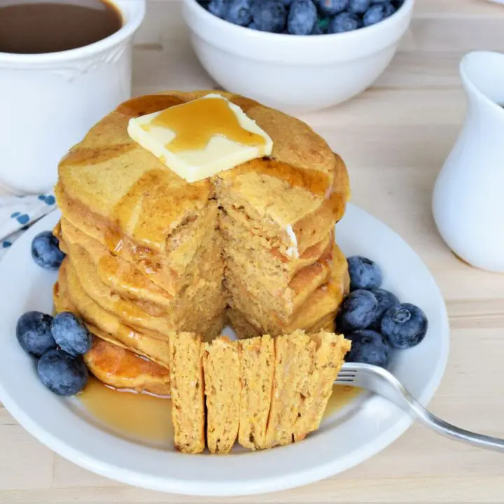 stack of butternut squash pancakes with butter and blueberries. Bite on a fork