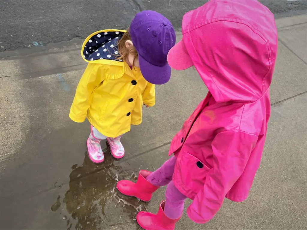Two girls splashing in puddles