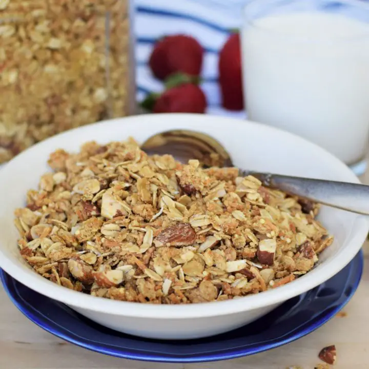Bowl of coconut almond granola in front of glass container of granola and glass of milk - this bread will rise