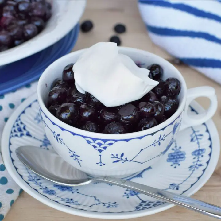 Tea cup full of roasted blueberries topped with whipped cream - this bread will rise