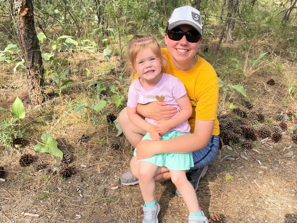 Mom holding daughter on her lap on a trail.