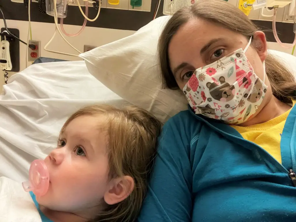 mom and young girl sitting on hospital bed