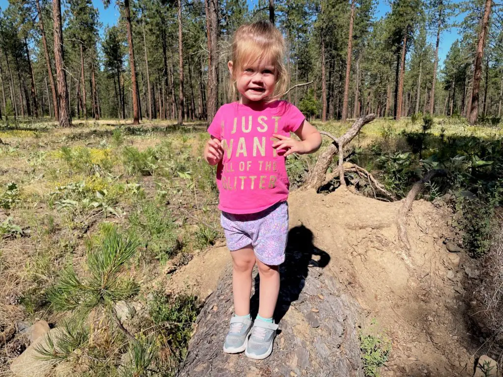 Girl standing on log with shirt that says "I just want all the glitter" -this bread will rise