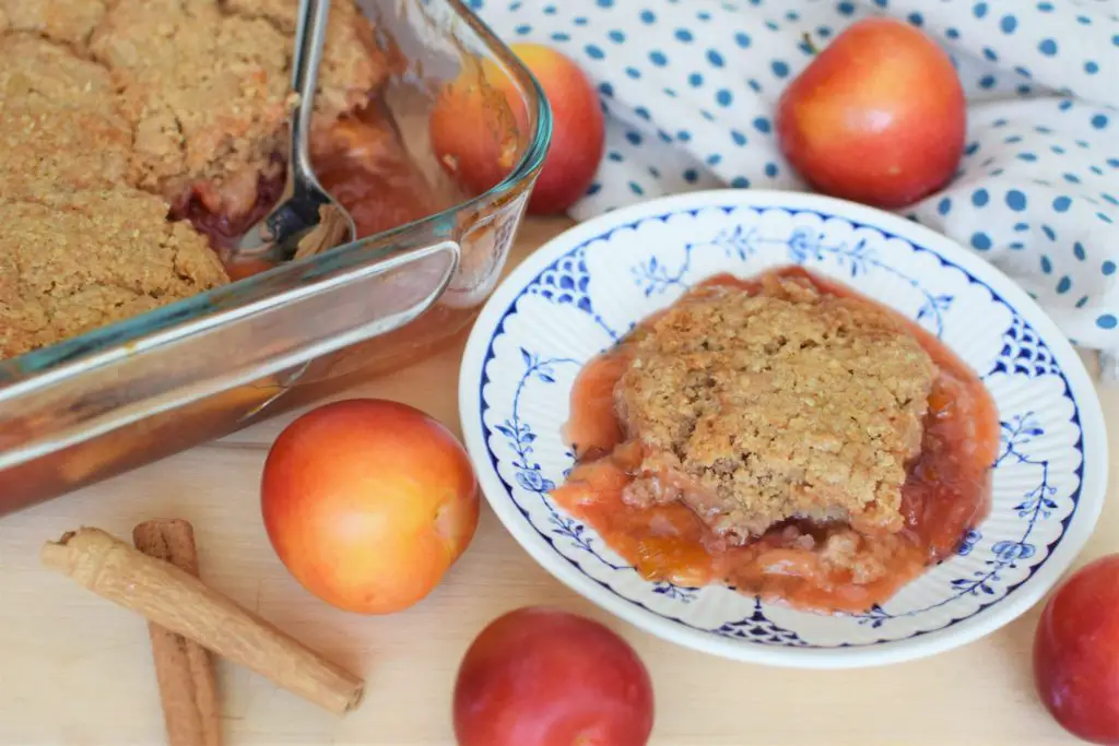 Dish of plum cobbler next to large baking pan of plum cobbler.