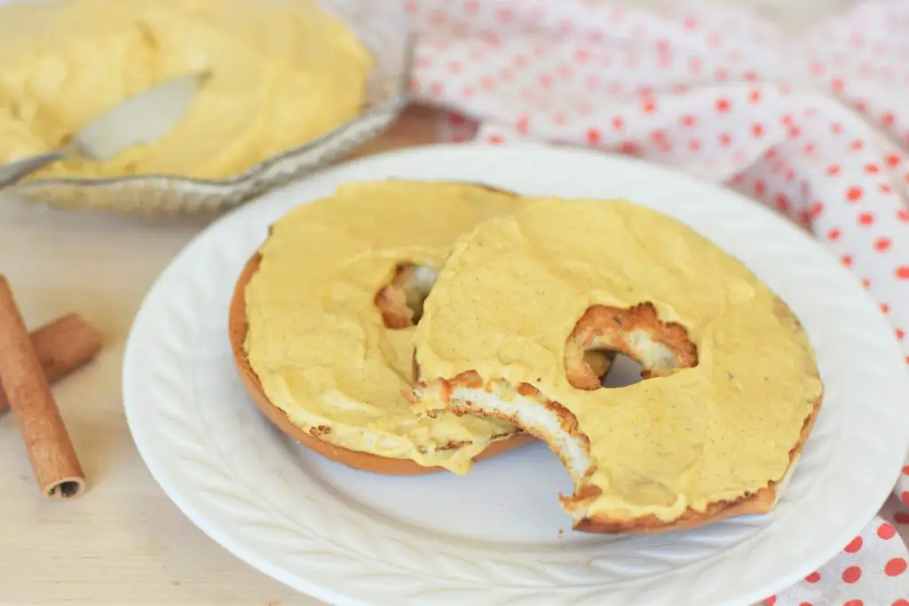 Bite taken out of bagel with pumpkin cream cheese - this bread will rise