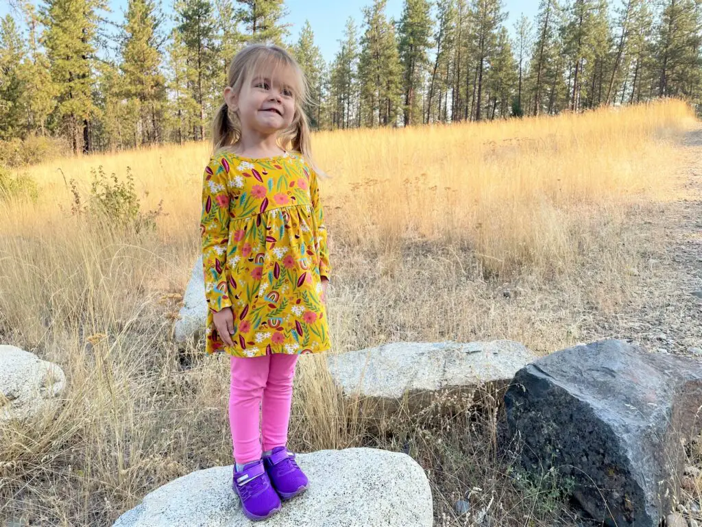 Girl standing on rock in a colorful outfit - this bread will rise