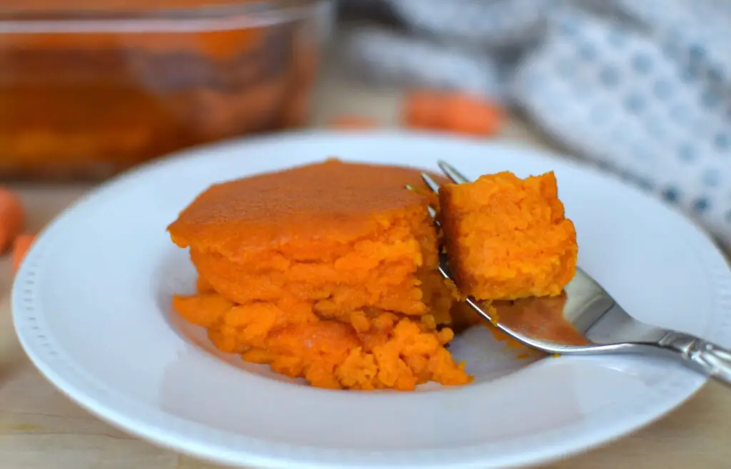 Carrot souffle on a plate with a fork scooping up a bite. This bread will rise