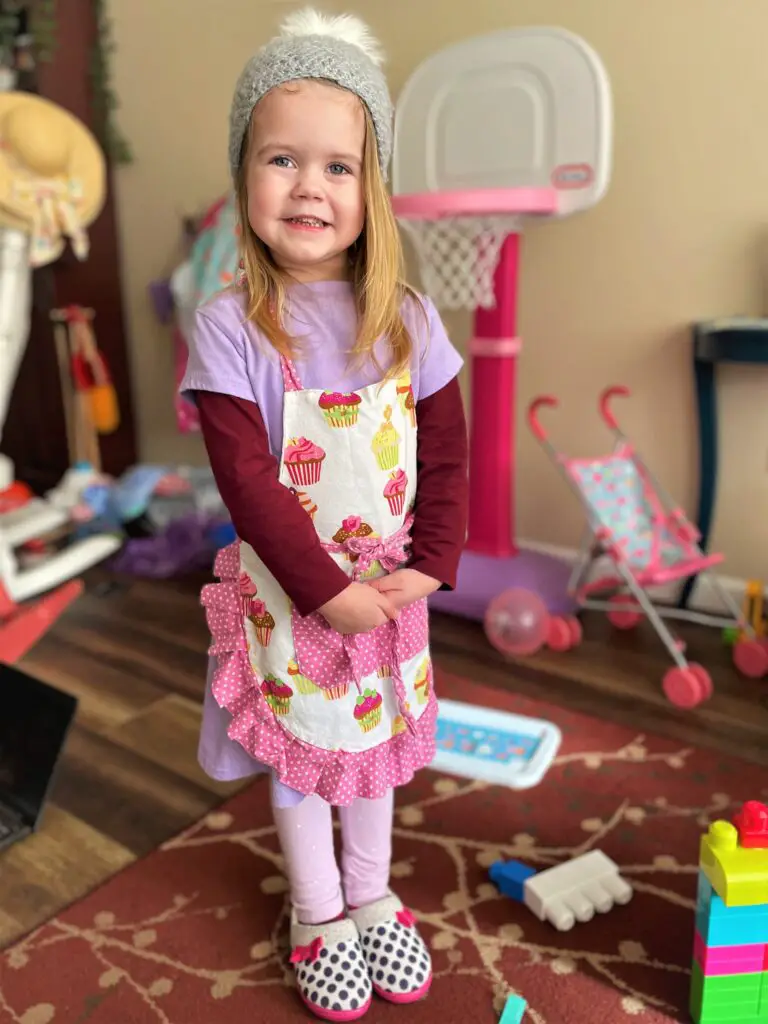 Girl with apron, hat, and slippers.