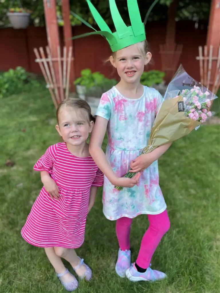 Two girls, one with a paper crown and flowers standing outside - this bread will rise