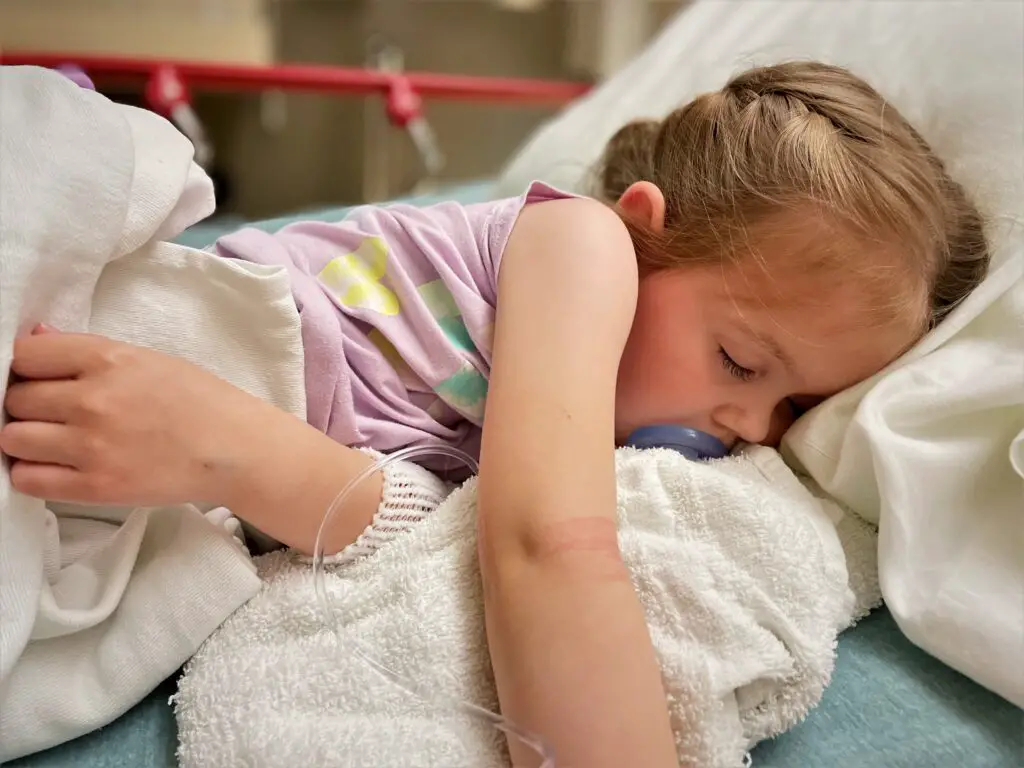 Young girl asleep on a hospital bed.