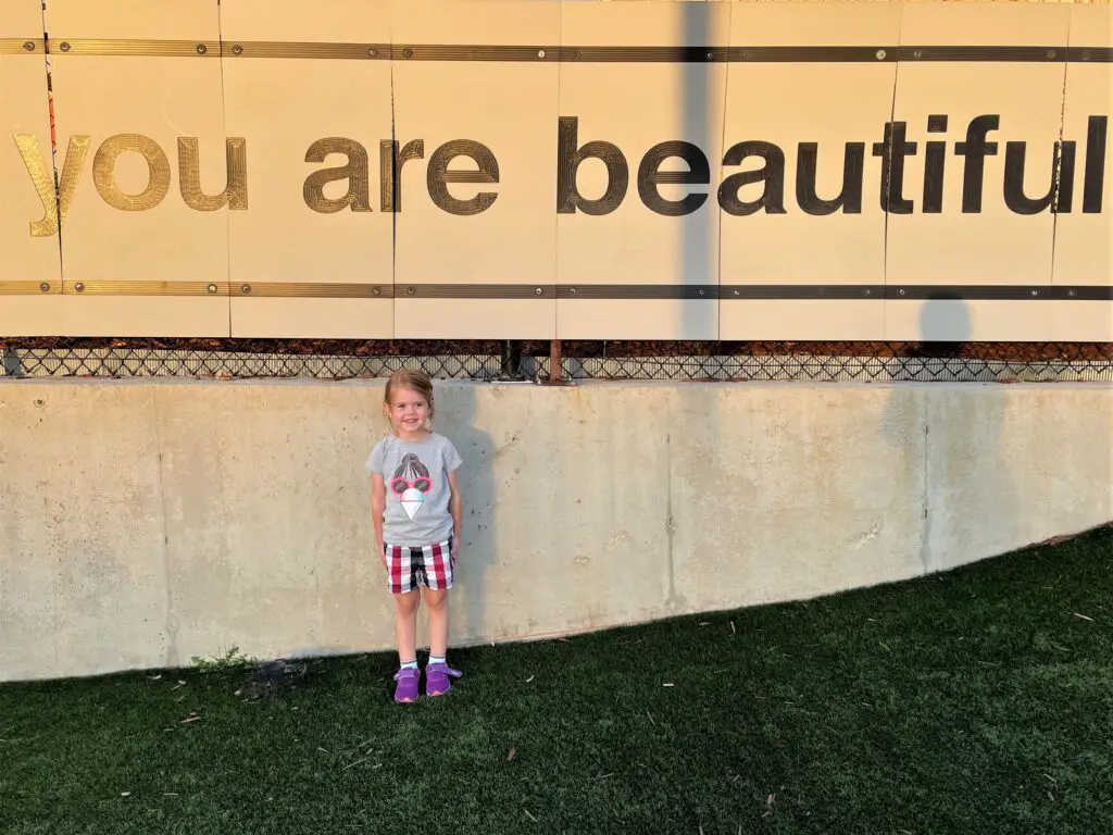 Ellie standing next to a sign that reads: "You are beautiful."