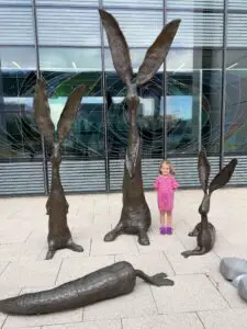 Ellie next to giant bunny statues.