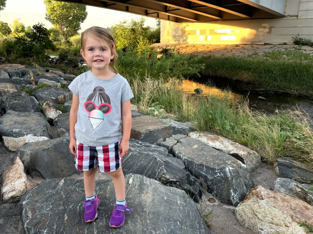 Ellie standing by a creek near a bridge.