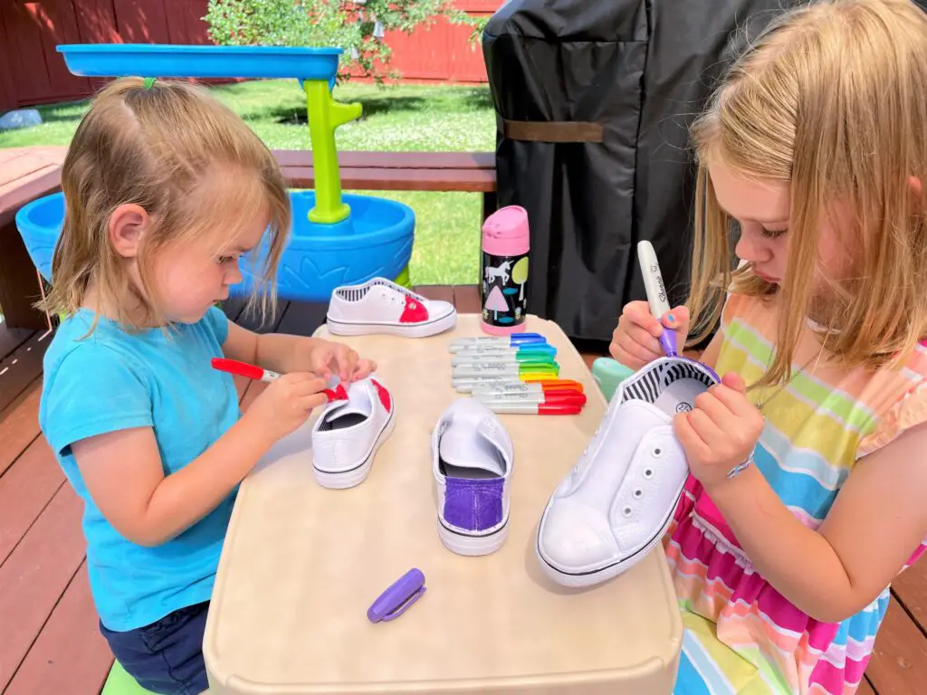 Ellie and Rosie coloring shoes at a picnic table.