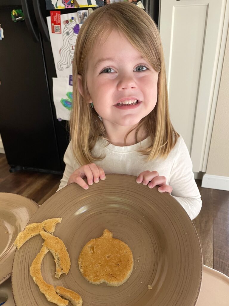 Ellie with almond flour pancake cut into a pumpkin